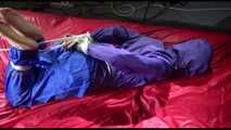 Sonja tied and gagged with ropes and a ballgag on a bed covered with a red shiny nylon cloth wearing a blue shiny nylon rain pants and a purple rain jacket (Video)