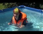 Mara wearing a sexy darkblue rain pants and rain jacket testing a life jacket in the swimmingpool (Video)