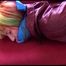 Mara tied and gagged on a red sofa wearing a sexy shiny bordeaux red oldschool skibib (Video)