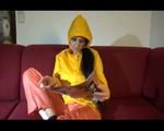 Lucy wearing an orange rain pants and a yellow rain jacket lolling on the sofa and reading a bit (Video)