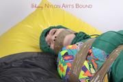 Jill tied and gagged with tape on bed wearing a shiny green nylon rainsuit (Pics)