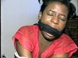 BLACK SHONDA IS RUBBER BAND BALL-GAGGED, MOUTH STUFFED, CLEAVE GAGGED & TIED BACKWARDS ON A CHAIR (D36-15)