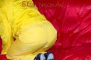 MARA wearing a sexy yellow shiny nylon rain suit lolling and posing on a bed (Pics)