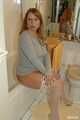 Chubby redhead Benita stripping out of a grey top and white stockings in the bathroom