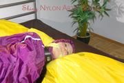 Lucy tied and gagged on a bar in bed wearing a sexy purple rainwear combination (Pics)