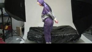 Pia bound and gagged on bed in a shiny purple/silver PVC sauna suit (Video)