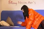 Mara wearing a sexy black down pants and an orange down jacket while lolling and reading on the sofa (Pics)