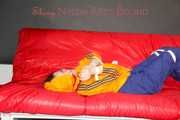 Lucy tied and gagged on a sofa wearing an orange shiny nylon rain jacket and a blue rain pants (Pics)