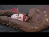 Simone tied and gagged on bed wearing a brown shiny nylon rainjacket and a rainpants (Video)