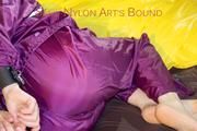 Lucy tied and gagged on a bar in bed wearing a sexy purple rainwear combination (Pics)