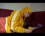 Lucy wearing an orange rain pants and a yellow rain jacket lolling on the sofa and reading a bit (Video)