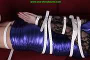 Sophie bound with Leatherbelts and Harnessgagged wearing a shiny purple Dress