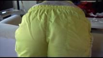 Mara tied and gagged bending over an sofa wearing a yellow shiny nylon shorts and a retro top (Video)