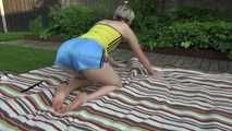 Watching sexy Sonja preparing a place for sun bathing and lolling in the garden wearing a sexy lightblue shiny nylon shorts and a yellow top (Video)