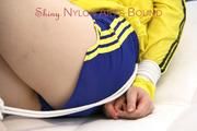 Mara tied and gagged on a white sofa wearing a sexy blue/yellow shorts and a yellow rain jacket (Pics)