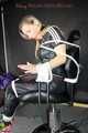 Sexy Sandra being tied and gagged on a haircutter`s chair with ropes and a ball gag wearing a supershiny sexy black rain bib overall (Pics)