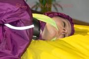 Lucy tied and gagged on a bar in bed wearing a sexy purple rainwear combination (Pics)