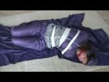 A video with Alina tied and gagged in a shiny purple and silver PVC suit