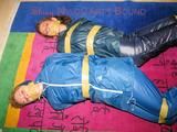 Stella and Leonie tied and gagged and hooded with tape both wearing sexy shiny nylon rainwear (Pics)