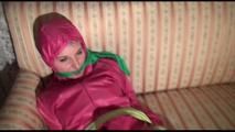 Mara tied and gagged with cloths on a sofa wearing sexy pink shiny nylon rainwear (Video)