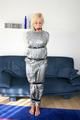 Blond-haired maid tied and gagged with tape wearing a shiny silver PVC sauna suit (Pics)
