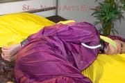 Lucy tied and gagged on a bar in bed wearing a sexy purple rainwear combination (Pics)
