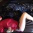 Lucy tied and gagged on bed wearing a darkred shiny nylon shorts and a red rain jacket (Video)
