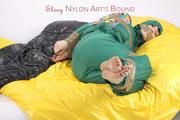 Jill tied and gagged with tape on bed wearing a shiny green nylon rainsuit (Pics)