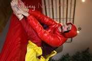 Watching sexy Jill wearing a red shiny nylon rain pants and an oldschool rain jacket under a red downjacket being tied and gagged with ropes and a ballgag on a bed (Pics)