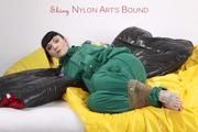 Jill tied and gagged with tape on bed wearing a shiny green nylon rainsuit (Pics)