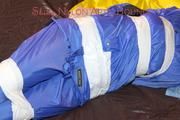 Lucy tied, gagged and hooded with tape by Sophie on bed wearing sexy lightblue rainwear (Pics)