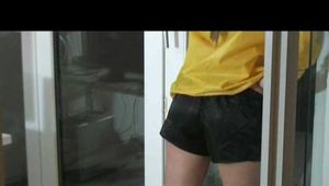 Brown-haired archive girl at homework wearing shiny nylon shorts and a rain jacket (Video)