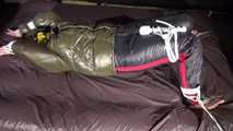 Watching Jill being tied on a bed wearing a shiny nylon rain jacket and a down jacket as well as a rain pants being double hooded and gagged with a ballgag (Video)