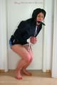 Katharina tied and gagged with a blue ball in a dark blue shiny nylon shorts with white stripes and a dark blue rain jacket