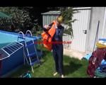 Mara wearing a sexy darkblue rain pants and rain jacket testing a life jacket in the swimmingpool (Video)