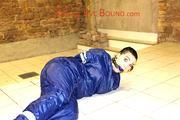 Jill tied and gagged in an old cellar on the floor wearing a shiny blue PVC sauna suit (Pics)