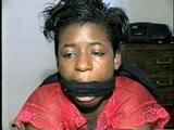 BLACK SHONDA IS RUBBER BAND BALL-GAGGED, MOUTH STUFFED, CLEAVE GAGGED & TIED BACKWARDS ON A CHAIR (D36-15)