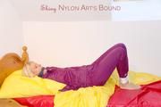 Pia in a shiny purple rainsuit tied and gagged in bed (Pics)