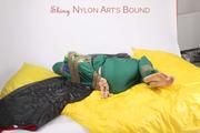 Jill tied and gagged with tape on bed wearing a shiny green nylon rainsuit (Pics)