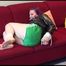 Mara tied and gagged on a red sofa wearing a green shiny nylon shorts and a shiny black rain jacket (Video)
