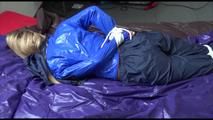 Samantha tied and gagged on bed wearing a shiny darkblue nylon rain pants and a light blue rain jacket (Video)