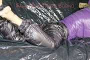 Sandra tied and gagged on a sofa with cuffs and a pillory wearing hot purple down jacket and black down pants (Pics)