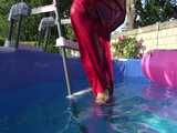 Watch Sandra watering the garden and wetting her shiny nylon oldschool Rainsuit in the Pool