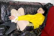 LUCY tied and gagged with ropes and a ballgag on a sofa wearing a sexy black/yellow shiny nylon shorts and a yellow rain jacket (Pics)