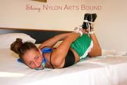 Stella tied and gagged on a bed in an hotel wearing a sexy green shiny nylon shorts and a top (Pics)