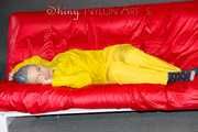 MARA wearing a sexy yellow shiny nylon rain suit lolling and posing on a bed (Pics)