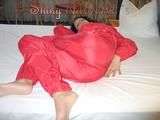 Brown-haired archive girl lolling on bed wearing a supersexy red shiny nylon rainwear combination (Pics)