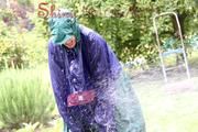Jill Diamond in the garden playing with water out of the garden hose wearing supersexy shiny nylon rainwear and a rain cape (Pics)