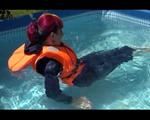 Mara wearing a sexy darkblue rain pants and rain jacket testing a life jacket in the swimmingpool (Video)