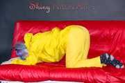 MARA wearing a sexy yellow shiny nylon rain suit lolling and posing on a bed (Pics)